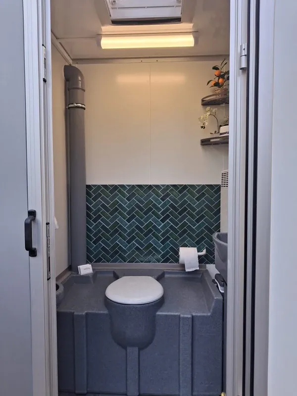 Innenansicht des Toilettenwagens mit Waschbecken, Beleuchtung und grün gefliester Wand